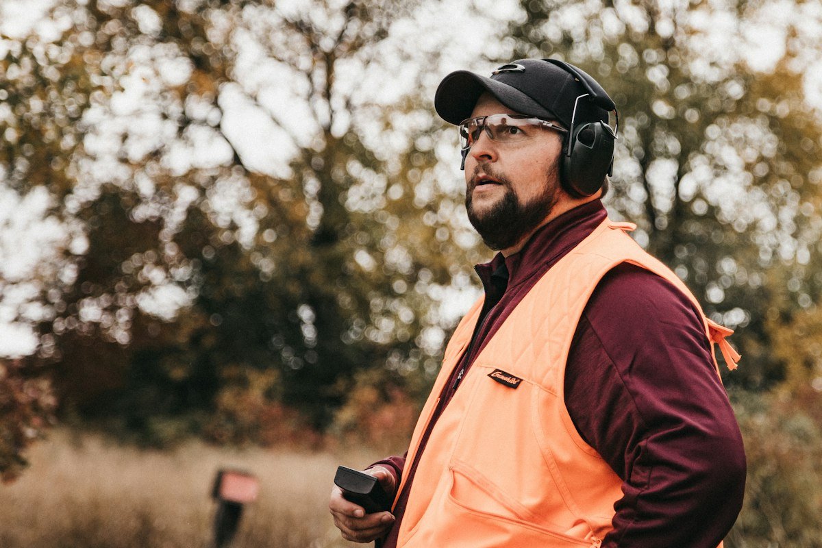 Worker in orange vest wearing ear defenders